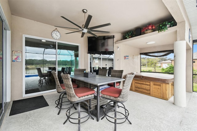 view of patio with outdoor dining area, a ceiling fan, and a hot tub