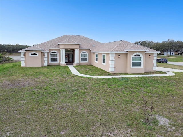 view of front of home with stucco siding, roof with shingles, and a front lawn