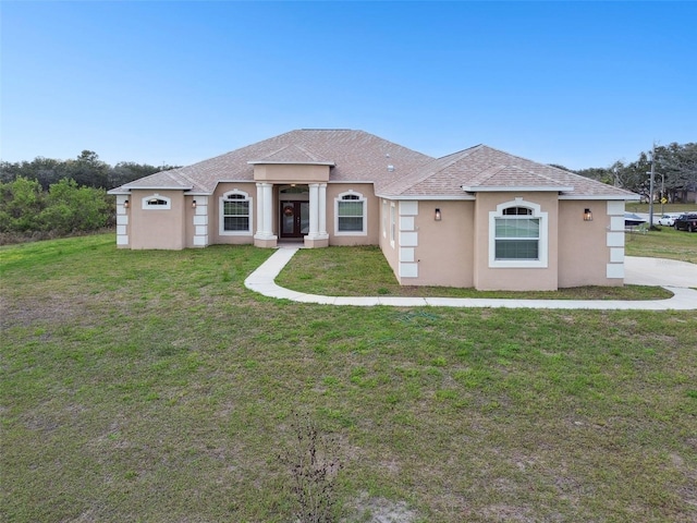 view of front of property featuring stucco siding, a front yard, and roof with shingles