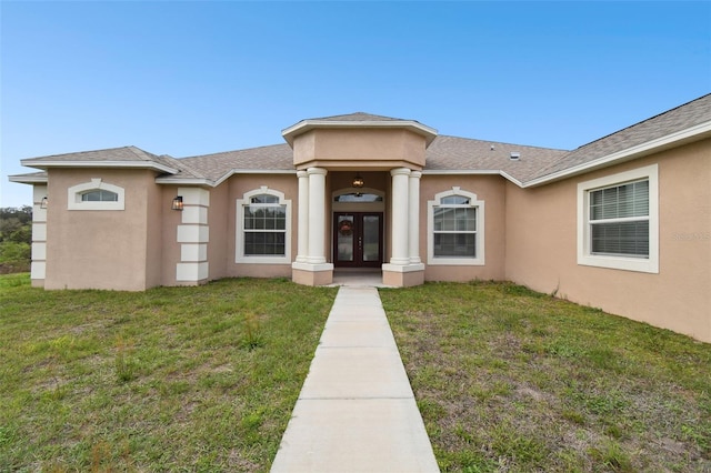 view of front facade featuring french doors, a front lawn, and stucco siding