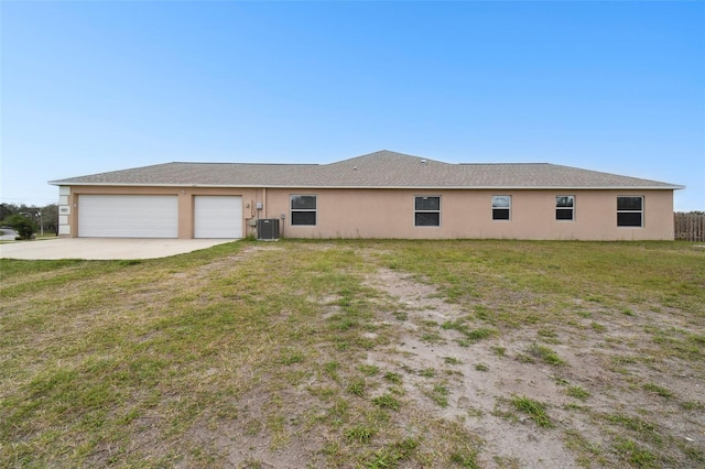 exterior space with stucco siding, driveway, a front yard, an attached garage, and central AC unit