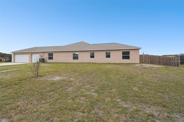 back of house with fence, central air condition unit, stucco siding, a lawn, and a garage