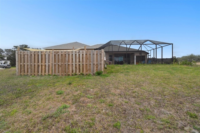 view of yard with glass enclosure and fence