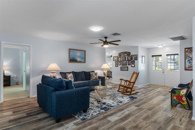 living area featuring visible vents, a textured ceiling, wood finished floors, and french doors