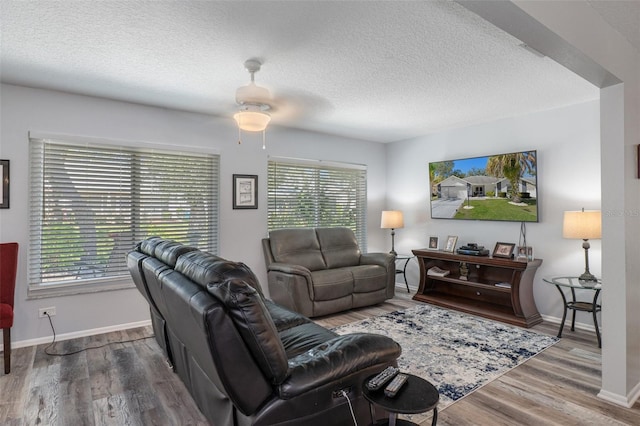 living room featuring baseboards, a textured ceiling, and wood finished floors