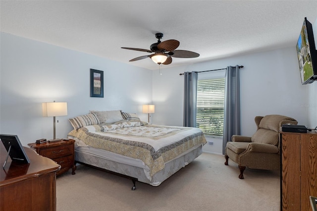 bedroom with light colored carpet, ceiling fan, and a textured ceiling