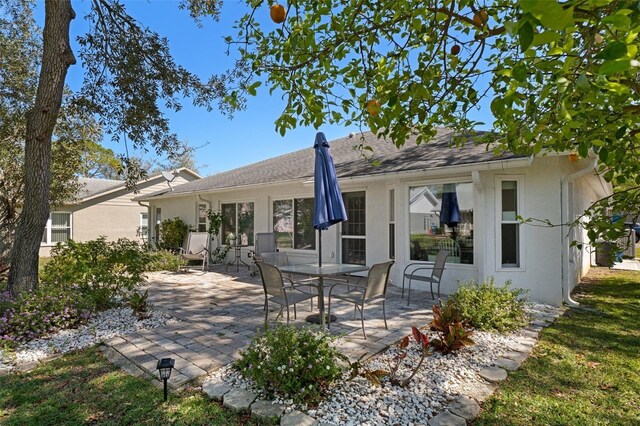 rear view of property with stucco siding and a patio