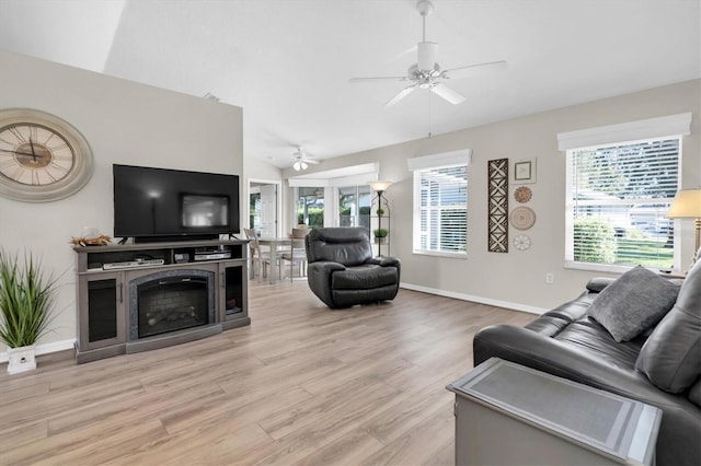 living area featuring a wealth of natural light, lofted ceiling, a ceiling fan, and light wood finished floors