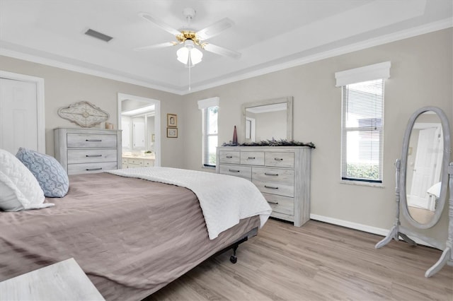 bedroom with visible vents, ornamental molding, light wood-style flooring, ensuite bath, and baseboards