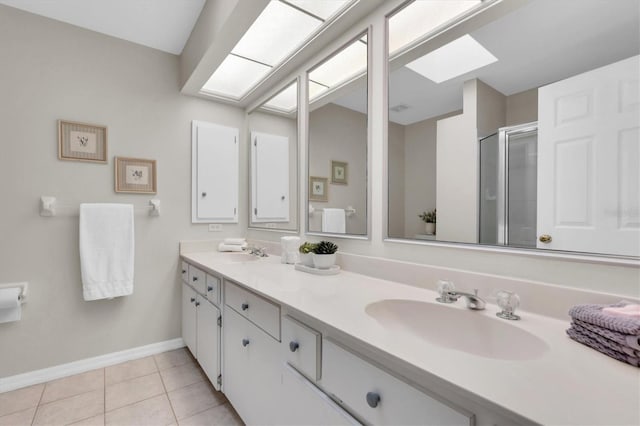 bathroom featuring tile patterned flooring, a shower stall, a skylight, and a sink