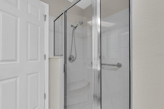 full bath featuring a shower stall and a textured wall