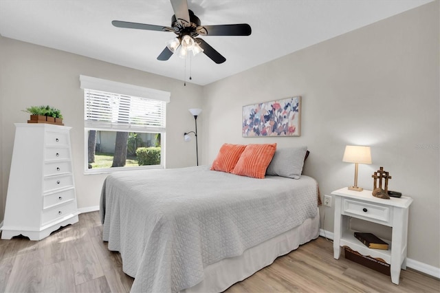 bedroom featuring baseboards, light wood-style floors, and a ceiling fan