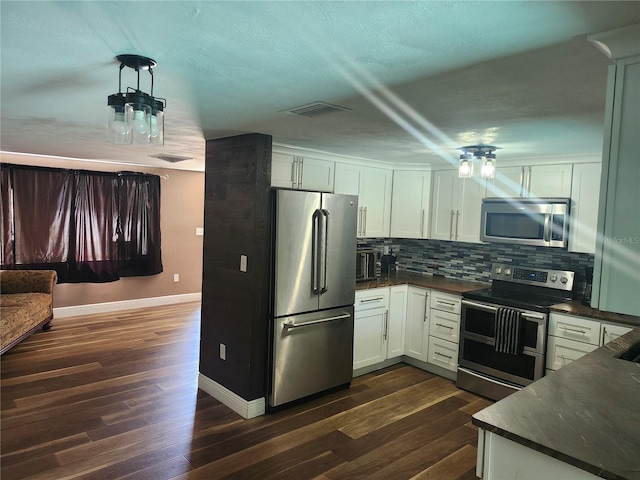 kitchen with dark countertops, stainless steel appliances, dark wood-type flooring, and decorative backsplash