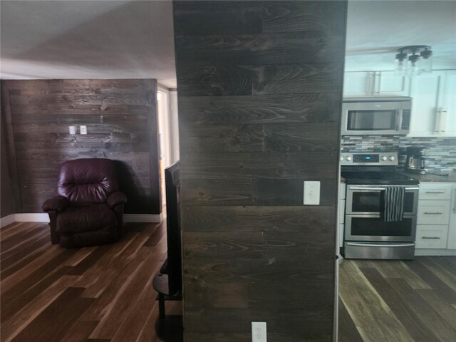 kitchen featuring dark wood-style floors, stainless steel appliances, white cabinets, and tasteful backsplash