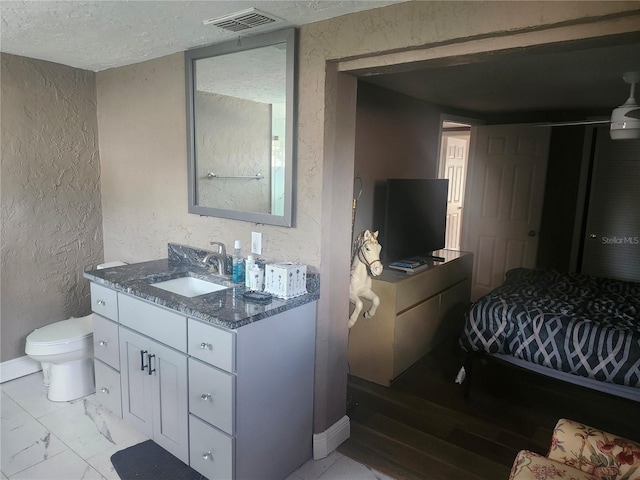 bathroom with a textured ceiling, visible vents, marble finish floor, vanity, and a textured wall