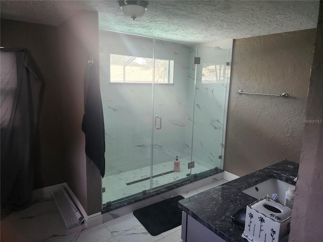 bathroom with marble finish floor, a textured wall, a marble finish shower, and a textured ceiling