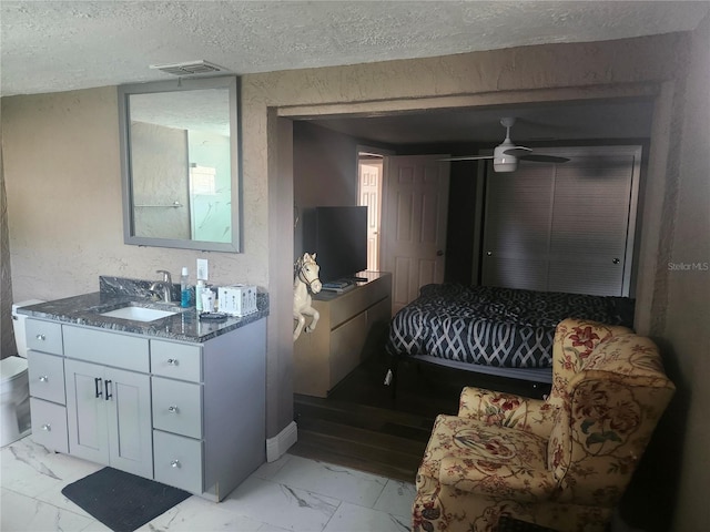 bedroom with marble finish floor, a sink, visible vents, and a textured ceiling