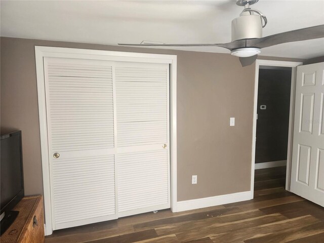 unfurnished bedroom featuring a ceiling fan, baseboards, a closet, and dark wood finished floors
