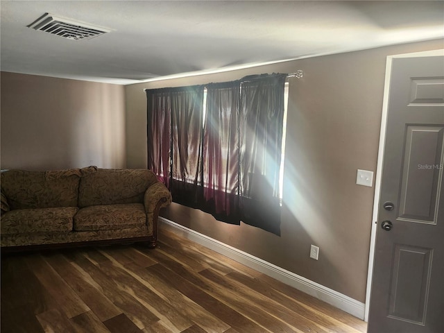 living room featuring baseboards, visible vents, and wood finished floors