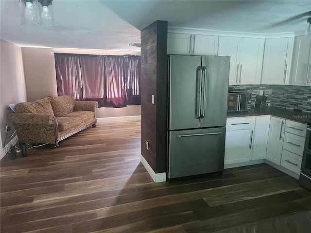kitchen with dark wood-style flooring, white cabinetry, tasteful backsplash, and freestanding refrigerator