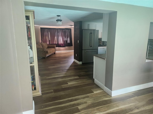 corridor with dark wood-style flooring and baseboards