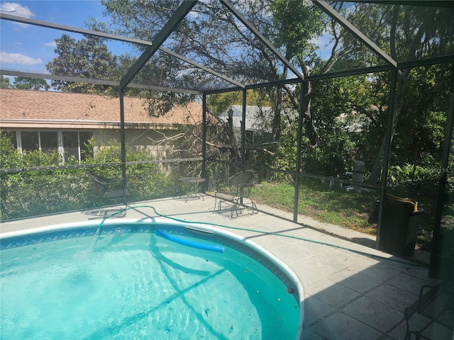 outdoor pool featuring a patio and glass enclosure