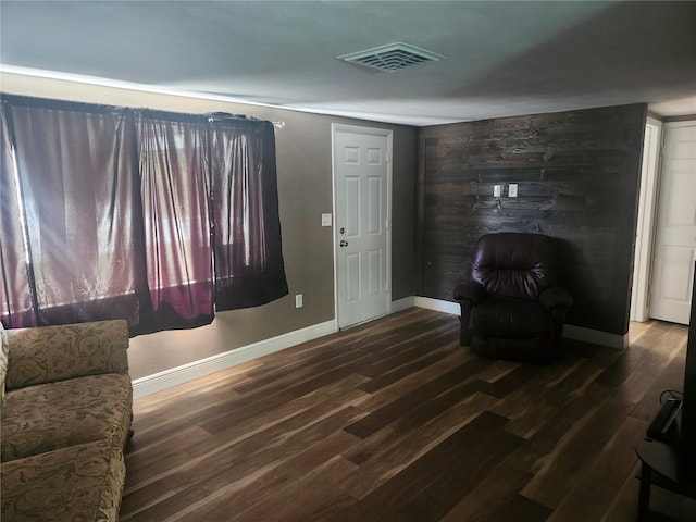 sitting room with baseboards, visible vents, wood finished floors, and wood walls