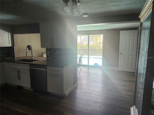 kitchen with white cabinets, a sink, dishwashing machine, dark wood-style floors, and backsplash
