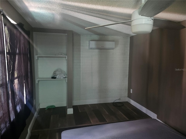bathroom with baseboards, wood finished floors, an AC wall unit, and a textured ceiling