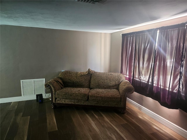living room with baseboards, visible vents, and wood finished floors