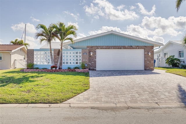 ranch-style home with a front lawn, a gate, decorative driveway, an attached garage, and brick siding