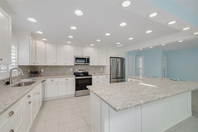 kitchen featuring a sink, backsplash, a center island, stainless steel appliances, and white cabinets