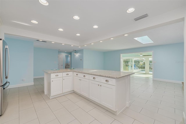 kitchen featuring visible vents, recessed lighting, a skylight, freestanding refrigerator, and white cabinets