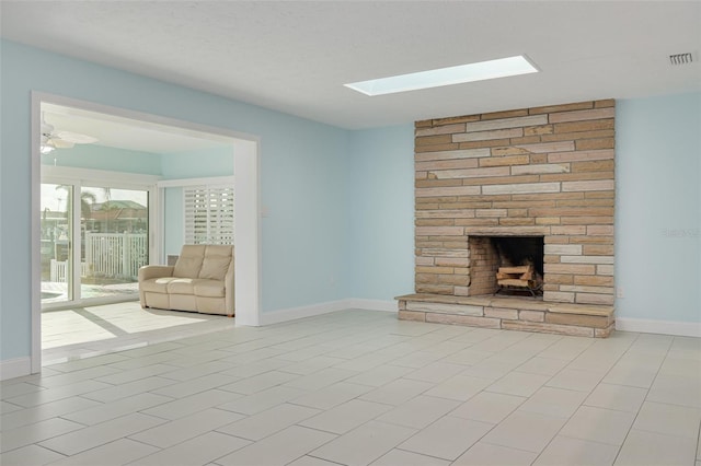 unfurnished living room with visible vents, a large fireplace, baseboards, and a skylight