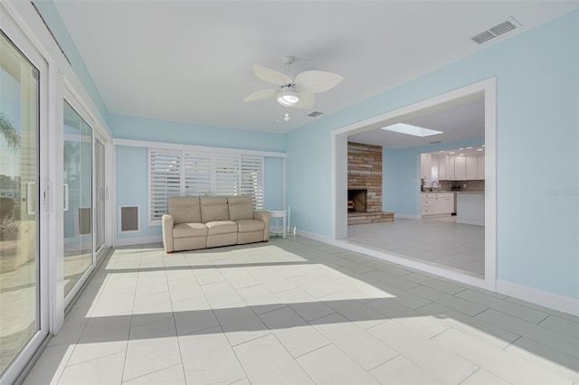 unfurnished room with light tile patterned floors, a ceiling fan, visible vents, and a large fireplace