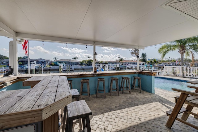 view of dock with a patio, fence, and outdoor dry bar