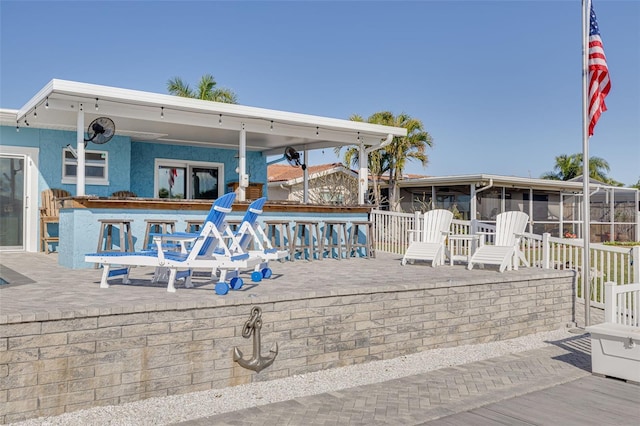 view of patio with outdoor dry bar and a sunroom