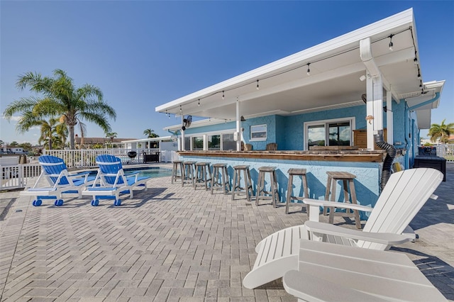 view of patio with outdoor dry bar and fence