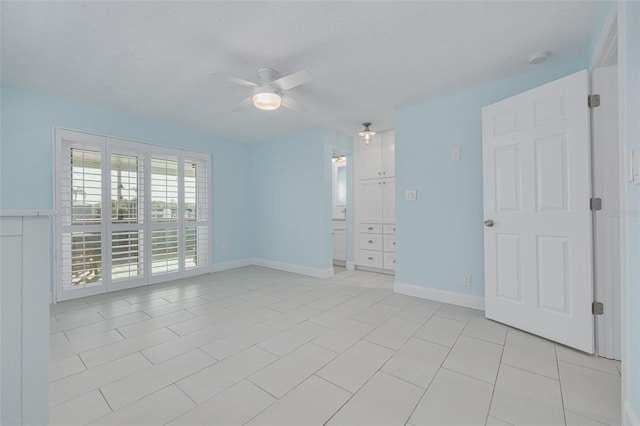 unfurnished room featuring a textured ceiling, light tile patterned floors, baseboards, and ceiling fan