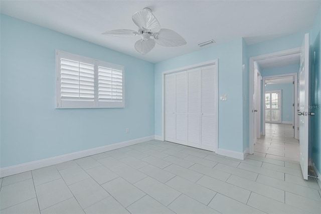 unfurnished bedroom with a ceiling fan, baseboards, visible vents, a closet, and tile patterned floors