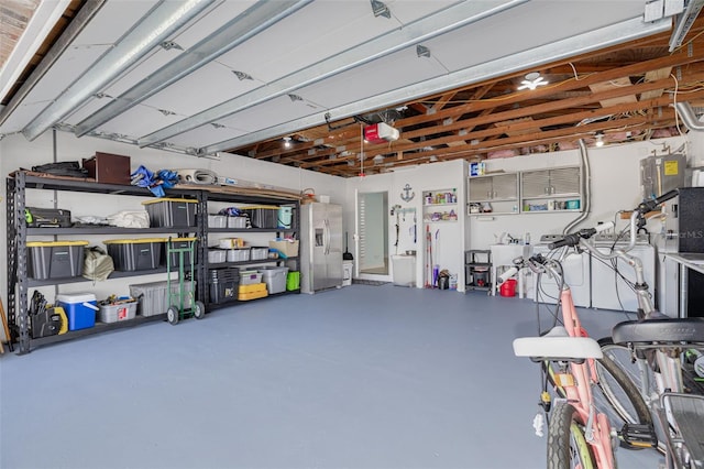 garage with a garage door opener and stainless steel refrigerator with ice dispenser