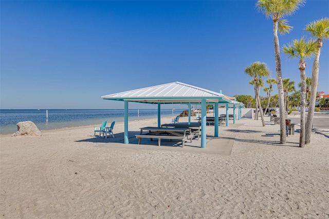 view of dock with a gazebo, a water view, and a beach view