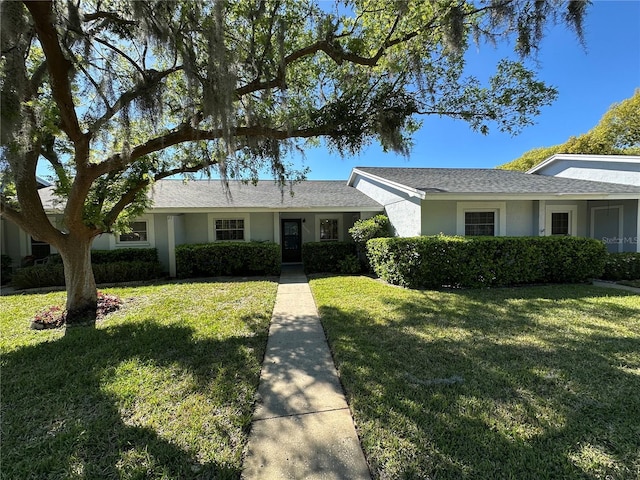 single story home with stucco siding and a front yard