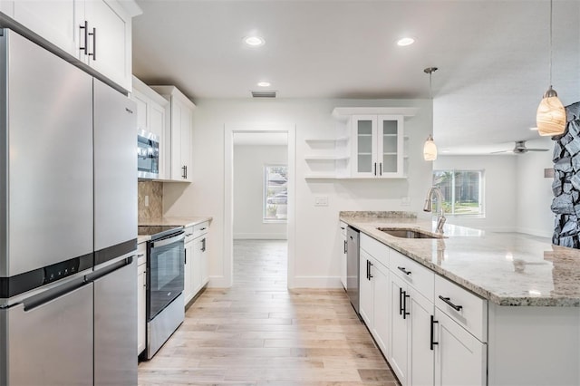 kitchen with visible vents, a sink, open shelves, appliances with stainless steel finishes, and a peninsula