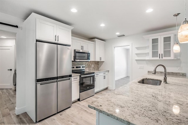 kitchen featuring visible vents, open shelves, a sink, appliances with stainless steel finishes, and a barn door