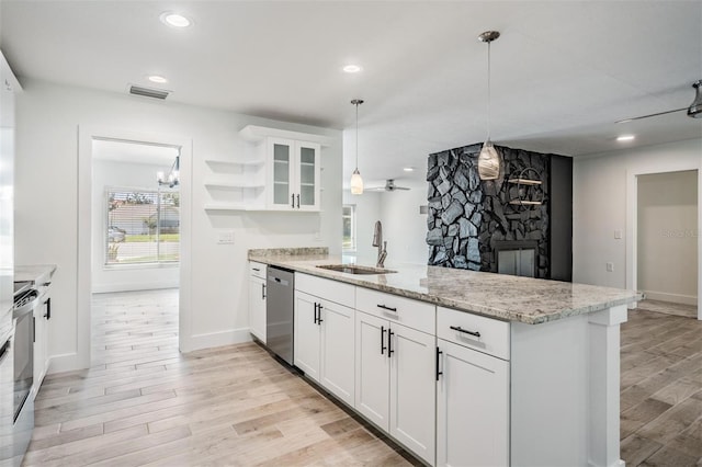 kitchen featuring a sink, stainless steel dishwasher, a peninsula, light wood finished floors, and range