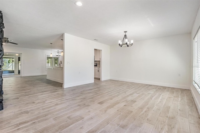 unfurnished room featuring baseboards, light wood-style floors, and an inviting chandelier