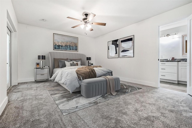 bedroom featuring light carpet, connected bathroom, a ceiling fan, and baseboards