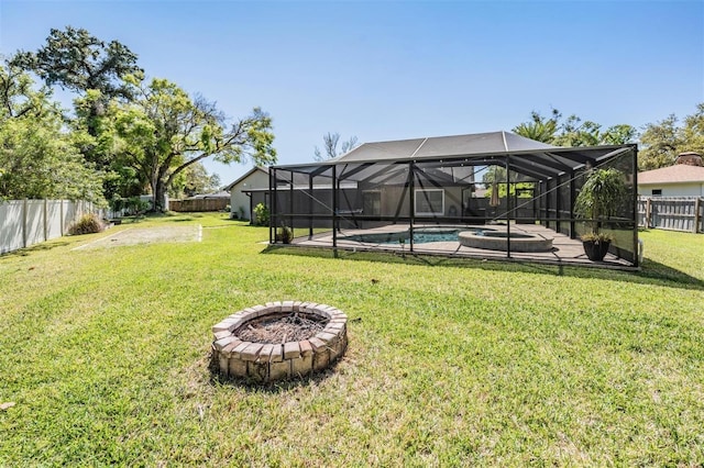 view of yard featuring glass enclosure, a fenced backyard, a pool with connected hot tub, and an outdoor fire pit