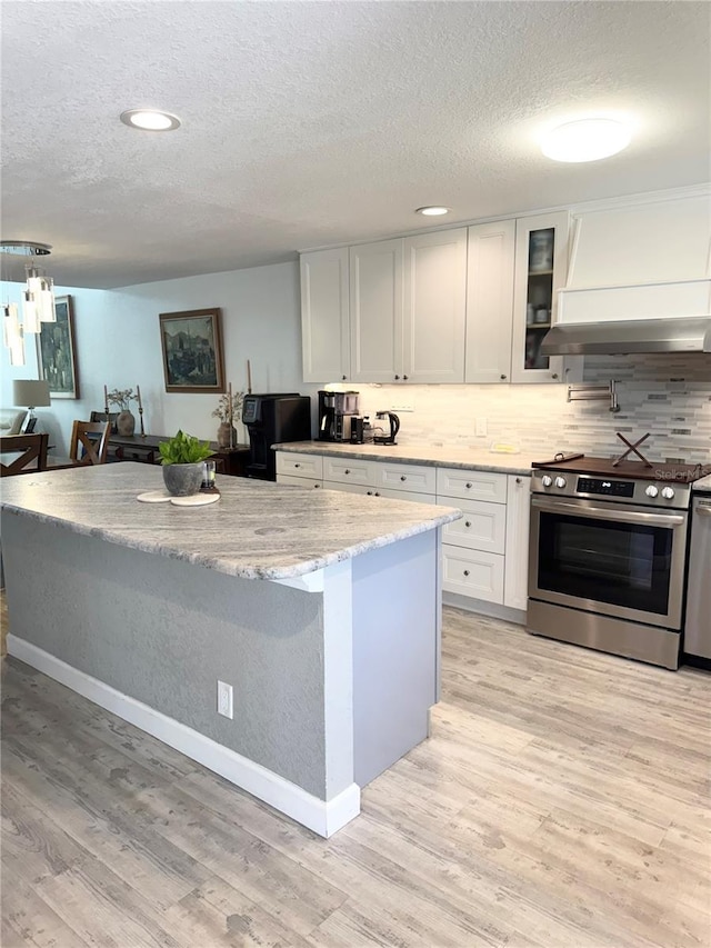 kitchen with premium range hood, stainless steel electric range, light wood-style floors, white cabinetry, and tasteful backsplash